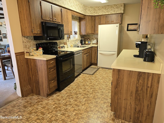 kitchen with a sink, black appliances, light countertops, and decorative backsplash