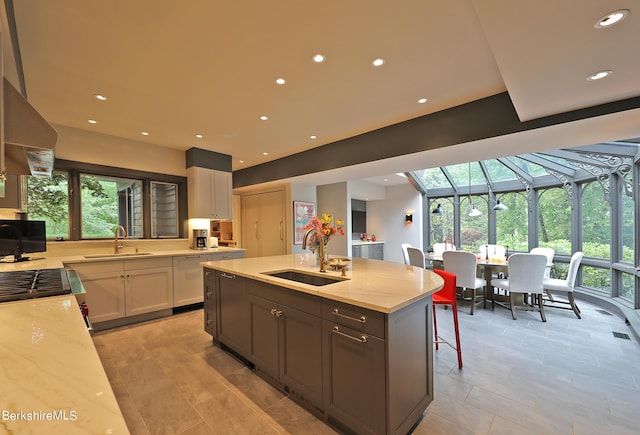 kitchen featuring a kitchen breakfast bar, light stone countertops, sink, and white cabinets