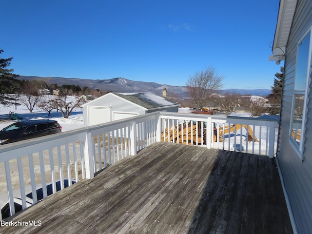 snow covered deck with an outdoor structure and a mountain view