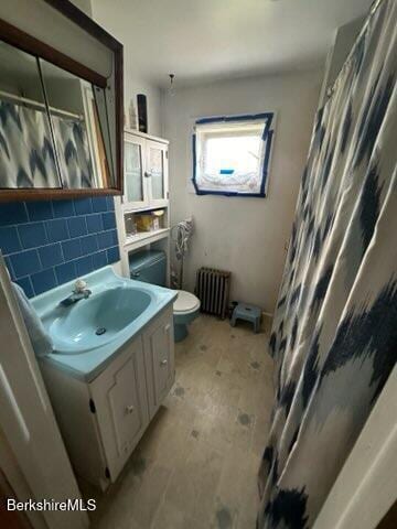 bathroom with decorative backsplash, radiator heating unit, vanity, and toilet