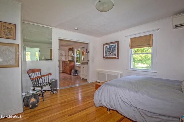 bedroom with a wall mounted air conditioner, light hardwood / wood-style floors, and radiator