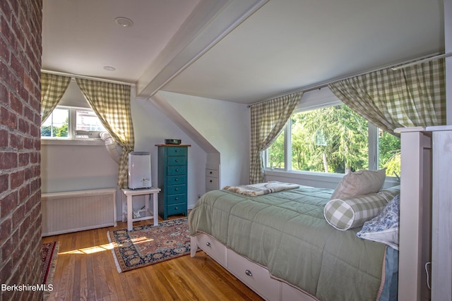 bedroom featuring beam ceiling, radiator, and wood-type flooring