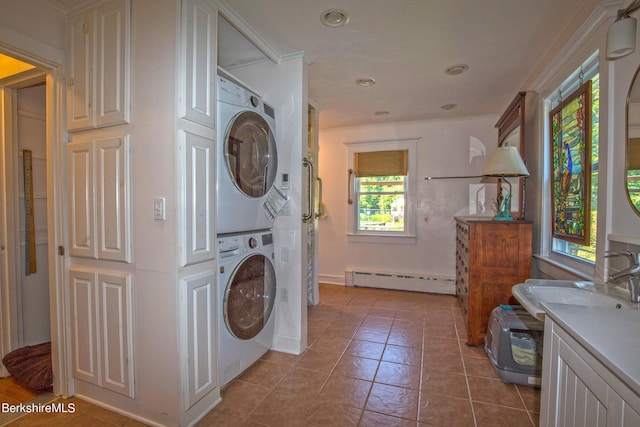 clothes washing area featuring a baseboard heating unit, sink, crown molding, light tile patterned floors, and stacked washer / drying machine