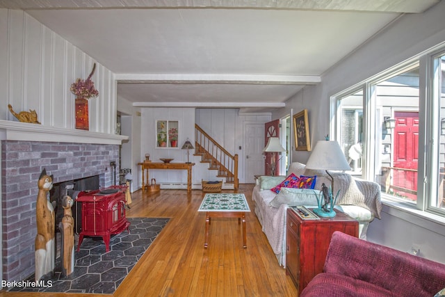 living room with hardwood / wood-style floors, a wood stove, baseboard heating, and beamed ceiling