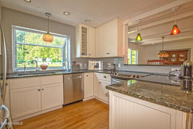 kitchen featuring sink, hanging light fixtures, stainless steel dishwasher, dark stone countertops, and white cabinetry