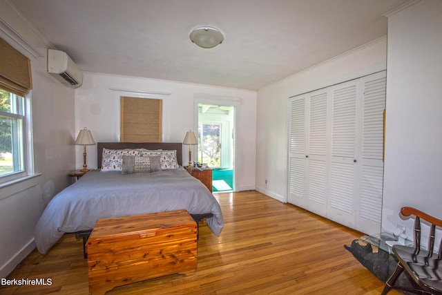 bedroom featuring a wall mounted air conditioner, light hardwood / wood-style flooring, and a closet