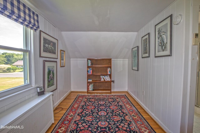 hallway with lofted ceiling, light wood-type flooring, and radiator heating unit