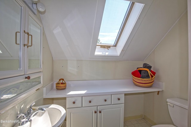 bathroom featuring toilet, lofted ceiling with skylight, and sink