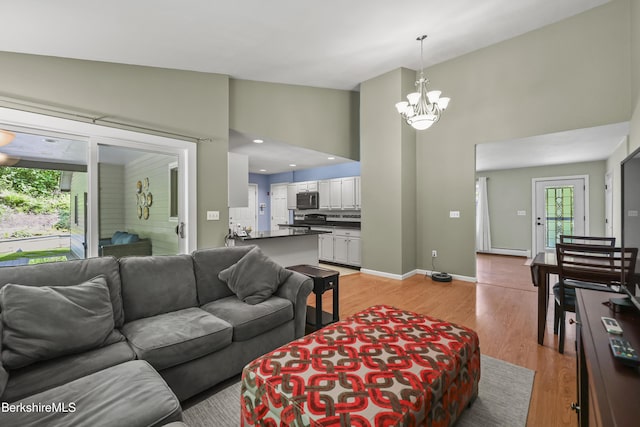 83 Bradley St, North Adams, MA 01247 - living room featuring a towering ceiling, a chandelier, light wood finished floors, and baseboard heating