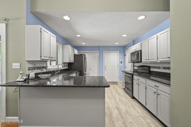 83 Bradley St, North Adams, MA 01247 - kitchen featuring appliances with stainless steel finishes, a peninsula, dark stone countertops, backsplash, and white cabinetry