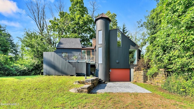 rear view of house featuring a lawn, a garage, stairway, a wooden deck, and driveway
