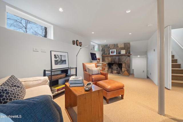 living area featuring light carpet, recessed lighting, a stone fireplace, and stairs