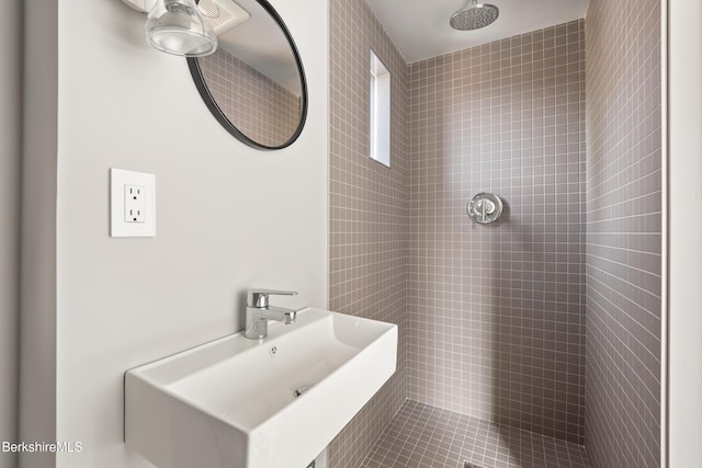 full bath with a sink and tiled shower