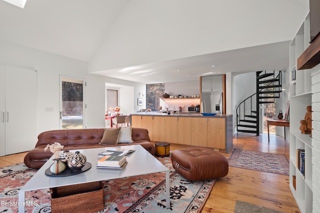 living room featuring high vaulted ceiling, light wood finished floors, a wealth of natural light, and stairway
