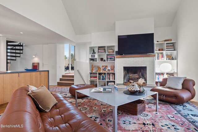 living area with wood finished floors, a fireplace, and stairway