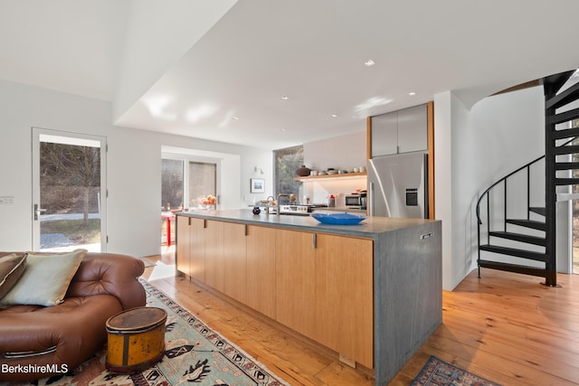 kitchen featuring open floor plan, light wood-type flooring, modern cabinets, and appliances with stainless steel finishes