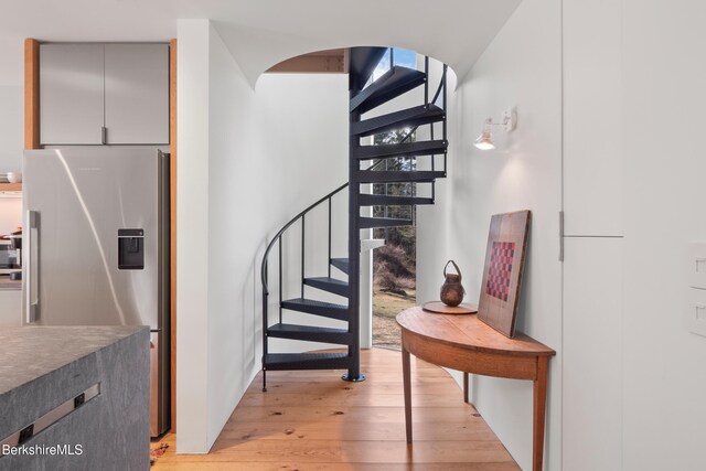 staircase with arched walkways and wood finished floors