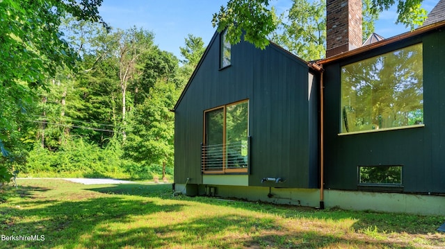 view of home's exterior featuring a chimney and a lawn