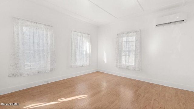 empty room featuring a wall unit AC, wood finished floors, and baseboards