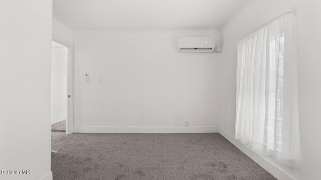 spare room featuring a wall unit AC, carpet flooring, baseboards, and ornamental molding