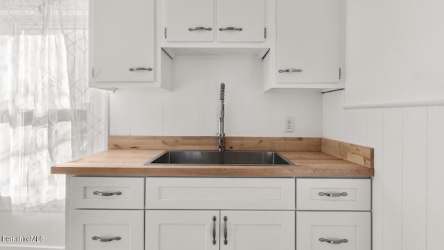 kitchen with white cabinets, butcher block counters, and a sink