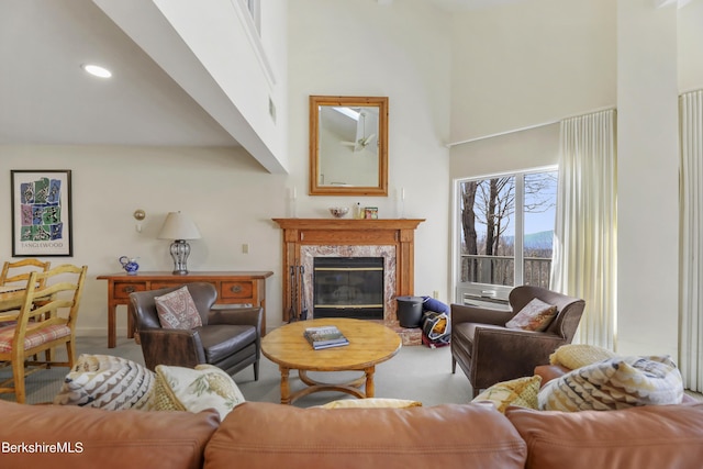 living room with a premium fireplace, carpet floors, and a high ceiling