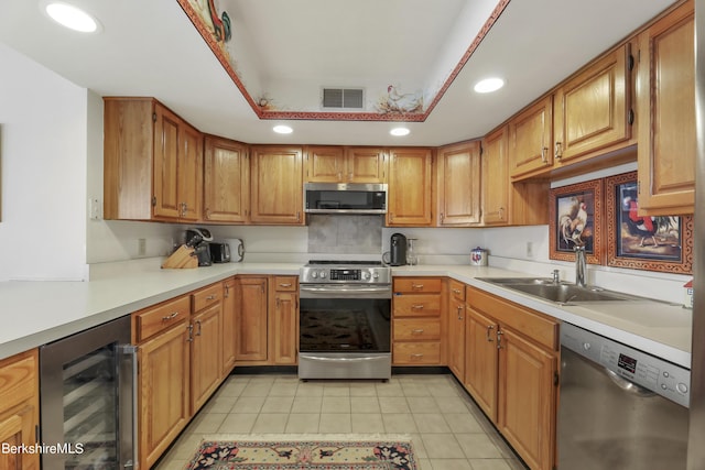 kitchen with sink, stainless steel appliances, a raised ceiling, light tile patterned flooring, and beverage cooler