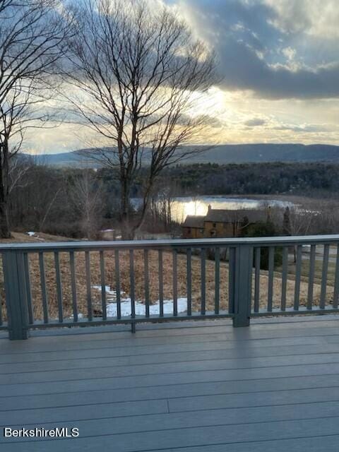 deck at dusk featuring a water view