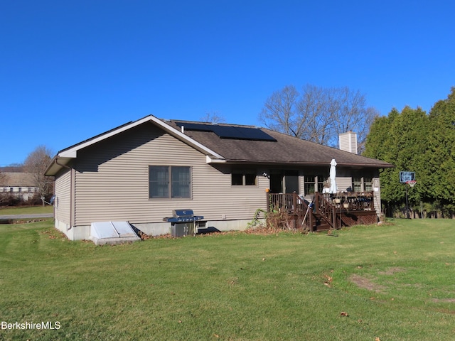 back of house featuring a lawn, solar panels, and a chimney