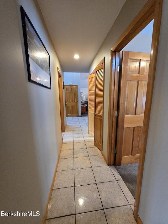 corridor with light tile patterned floors and baseboards