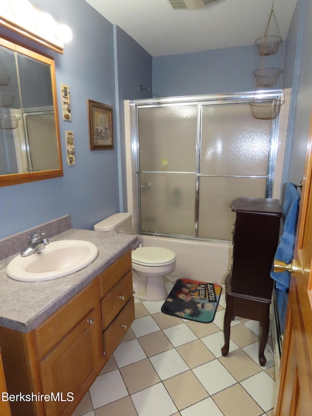 full bath featuring vanity, toilet, and bath / shower combo with glass door