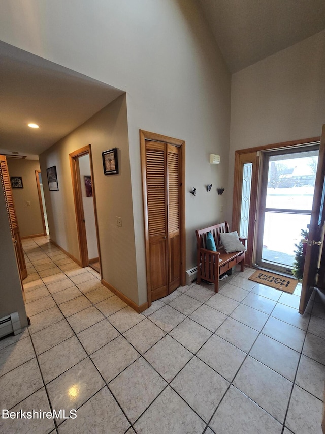 tiled foyer featuring a towering ceiling and a baseboard radiator