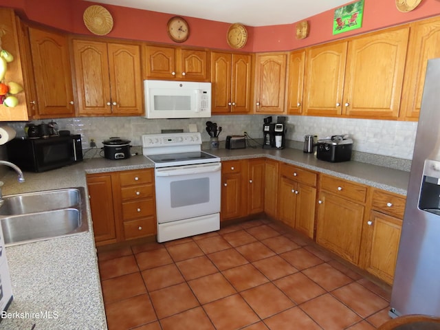 kitchen featuring a sink, decorative backsplash, white appliances, and light countertops