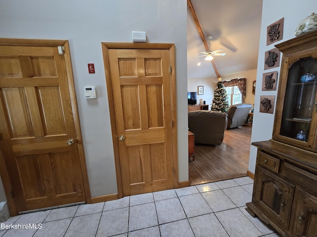 hall featuring light tile patterned floors and vaulted ceiling