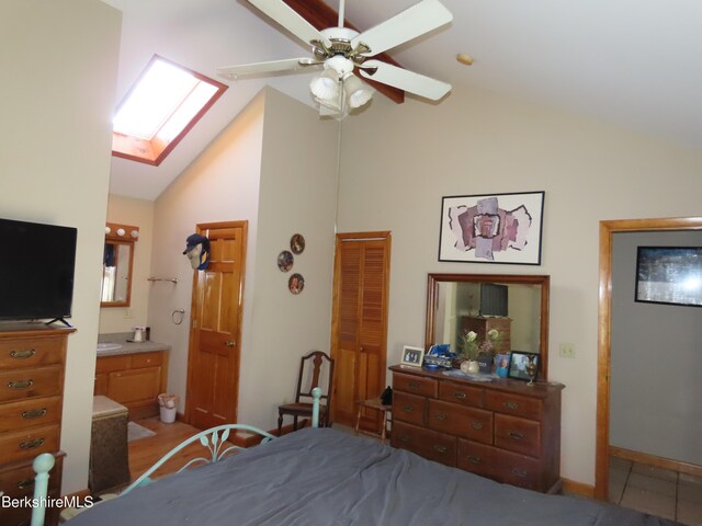 bedroom with lofted ceiling with skylight, ensuite bathroom, and ceiling fan