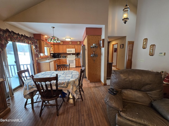 dining area with light hardwood / wood-style floors, sink, and vaulted ceiling