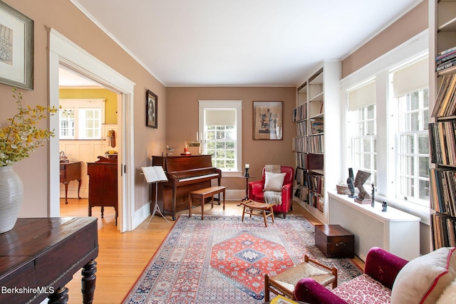 sitting room with baseboards, ornamental molding, and light wood finished floors