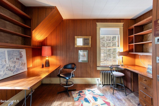 office space with wood finished floors, wood walls, and built in study area