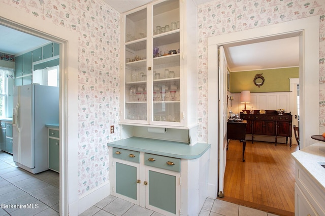 kitchen featuring light tile patterned floors, wallpapered walls, light countertops, and white fridge with ice dispenser