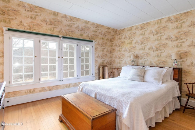 bedroom featuring wallpapered walls, baseboards, and wood-type flooring