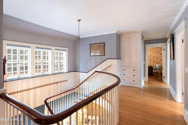 hall featuring an upstairs landing, wainscoting, and light wood finished floors