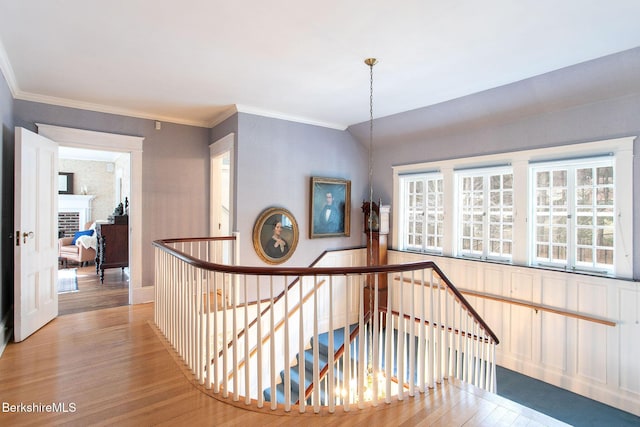 stairway featuring crown molding, a brick fireplace, wood finished floors, and vaulted ceiling