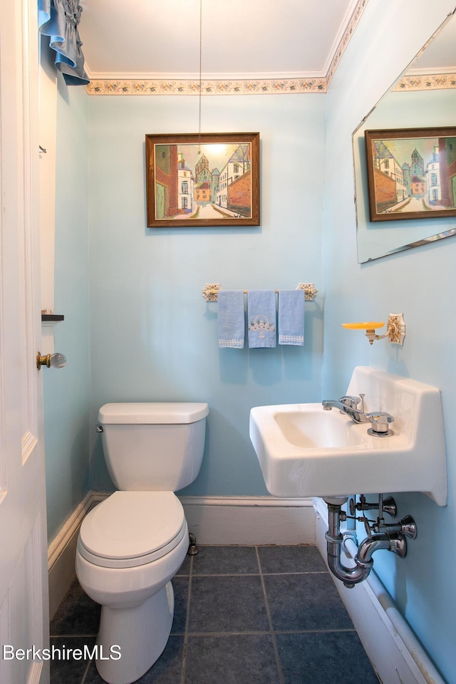 half bath featuring tile patterned flooring, toilet, and baseboards