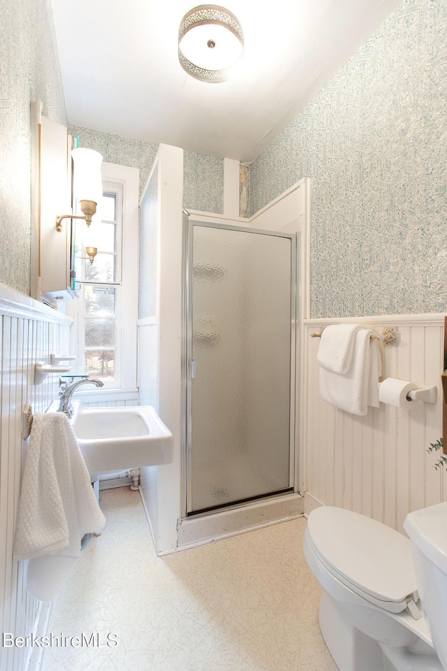 bathroom featuring toilet, a stall shower, and wallpapered walls