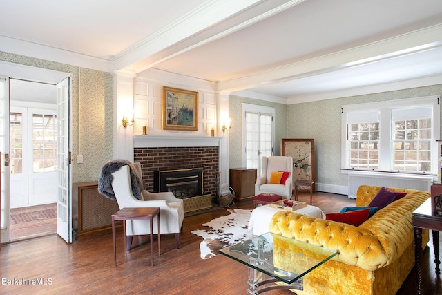 living room featuring a brick fireplace, radiator, wallpapered walls, and wood finished floors