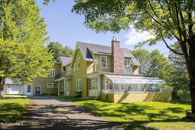 82 W Ave, Great Barrington, MA 01230 - view of front of home with stucco siding, a chimney, a front lawn, roof with shingles, and a balcony