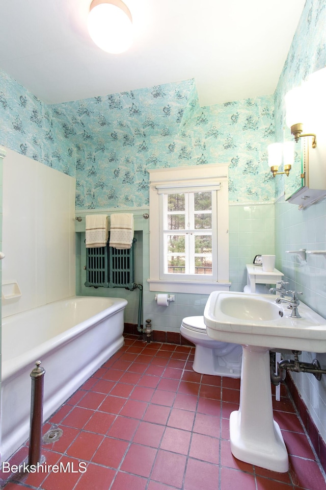 full bathroom with a wainscoted wall, wallpapered walls, a tub, tile patterned floors, and toilet