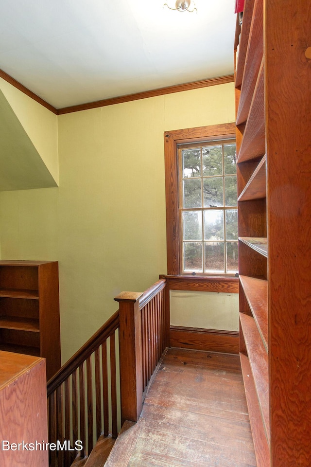 stairs with crown molding and wood finished floors