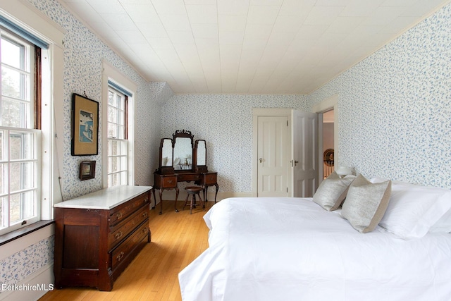 bedroom featuring multiple windows, light wood-style flooring, and wallpapered walls