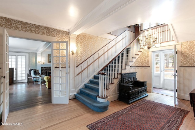 stairway with hardwood / wood-style floors, french doors, wallpapered walls, and ornamental molding